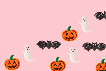 Smiling pumpkin, ghost and black bat on pink background. Funny Halloween celebration party idea with copy space.