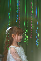 A portrait of a sweet, beautiful, laughing little 7-year-old girl in a white dress, with a white...