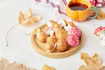 Autumnal wooden dish with marshmallow mushrooms, tea cup, arrangement of fall decorations, delights