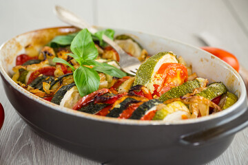 prepared baked zucchini and tomatoes in circles in a ceramic form, vegetable snack