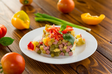vegetable salad of boiled vegetables, with peas, sausage, sweet pepper. On a wooden table