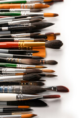 Obraz premium Mix of paint brushes in a row isolated on a white background. Top view.