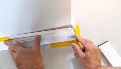 Man installing new skirting board - DIY home work concept