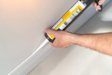 Man installing new skirting board - DIY home work concept
