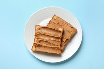 Delicious sandwiches with peanut butter on light blue table, top view