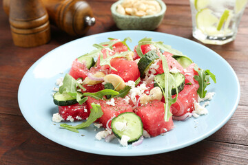 Tasty salad with watermelon, feta cheese, cashews and arugula on wooden table