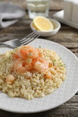 Delicious risotto with shrimps and cheese on wooden table, closeup