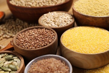 Different types of seeds and cereals in bowls on table, closeup