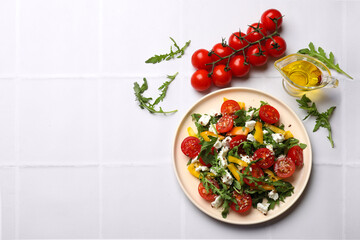Tasty salad with arugula, cheese and vegetables on white tiled table, flat lay. Space for text