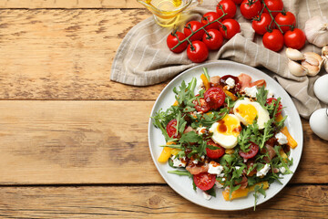 Tasty salad with arugula, egg, cheese and vegetables on wooden table, flat lay. Space for text