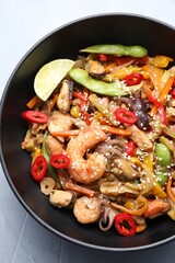 Stir-fry sea food in bowl on light grey table, top view