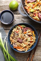 Stir-fry noodles with sea food and vegetables served on wooden table, flat lay