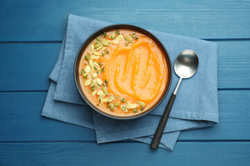 Delicious sweet potato soup with pumpkin seeds on blue wooden table, top view