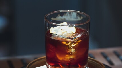 Closeup cocktail whiskey in Old fashioned with cube ice decorated dried sliced apple on top making special drink list, advertisement focusing alcohol refreshing showcase copy space at club. Vinosity.
