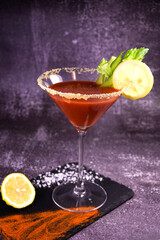 Bloody Mary alcoholic cocktail decorated with hot pepper and celery on a dark background. Serving a drink at the bar.