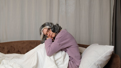 Fototapeta premium A woman in pajamas is sitting on the bed.