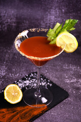 Bloody Mary alcoholic cocktail decorated with hot pepper and celery on a dark background. Serving a drink at the bar.