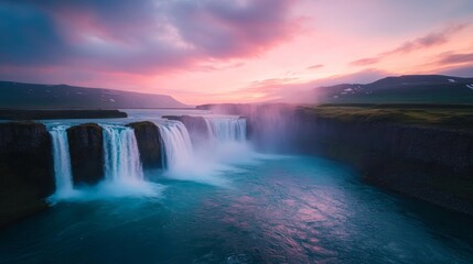 Fototapeta premium A serene waterfall cascading into a tranquil river, illuminated by a colorful sunset.