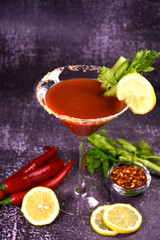 Bloody Mary alcoholic cocktail decorated with hot pepper and celery on a dark background. Serving a drink at the bar.