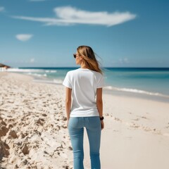 Woman in White T-Shirt and Jeans Stands on Sandy Beach Facing Ocean