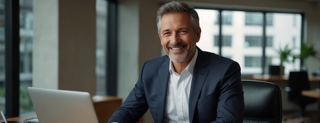 Smiling mature adult business man executive sitting at desk using laptop. Happy busy professional mid aged businessman ceo manager working on computer corporate technology in office