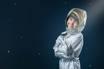 A young child in a silver spacesuit is smiling and posing for a picture