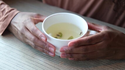 Women's hands hold a mug of hot tea in the morning during the cold season. A young woman warms her hands on a very hot cup of tea.