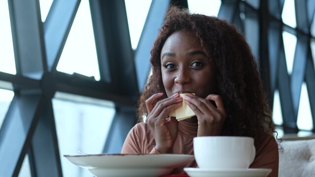 Such delicious tasty filling food. Close-up of a curly-haired beautiful woman tasting food in a new restaurant.