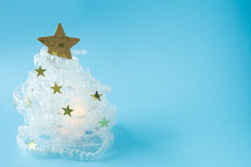 Christmas tree made with clear dental aligners. A Christmas tree made of clear beads and a gold star sits on a blue background. The tree is surrounded by white glitter, giving it a festive and sparkli