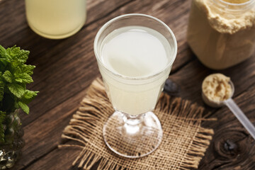 Fresh natural whey in a glass cup and a jar of whey protein powder