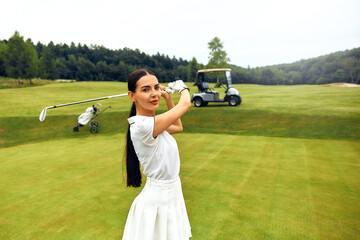 A cheerful and smiling golfer practicing their swing on the beautiful golf course today