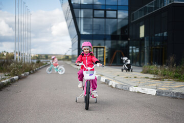 Young girl riding a bike with training wheels in a cityscape