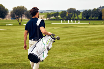 A Golfer is Walking on the Golf Course with His Clubs as He Enjoys the Beautiful Day
