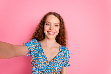 Smiling woman taking a cheerful selfie against pink background