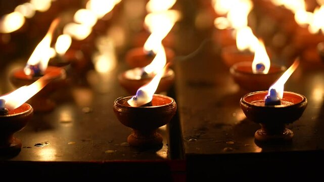 Lighting many candles in temples, religion, prayers and the concept of God. Close-up view of a burning flame on a candle isolated on black background.