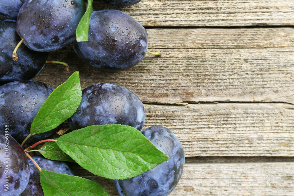 Canvas Prints Tasty ripe plums and leaves on wooden table, flat lay. Space for text