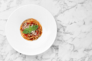 Delicious pasta bolognese with basil on white marble table, top view. Space for text
