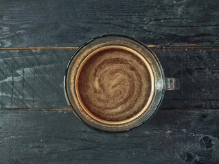 A cup of black coffee on the wooden table on top view 