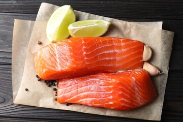 Pieces of fresh salmon, garlic, lime and spices on wooden table, top view