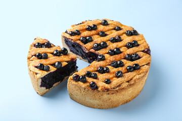 Cut homemade blueberry pie on light blue background