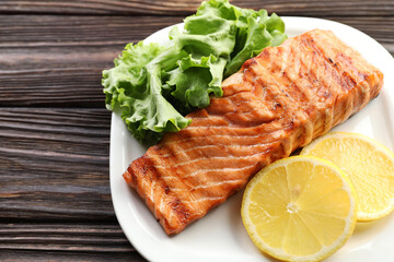 Delicious grilled salmon fillet served on wooden table, closeup