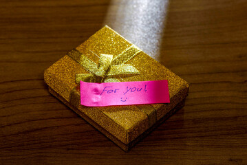 Gift box with a note on a wooden table surface.