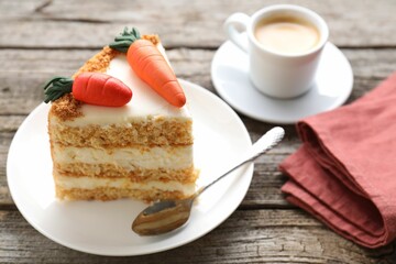 Piece of delicious carrot cake served with coffee on wooden table, closeup