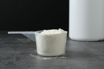 Protein powder in scoop on grey textured table