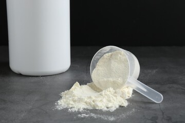 Protein powder in scoop on grey textured table