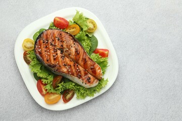 Tasty grilled salmon steak and vegetables on light grey table, top view. Space for text