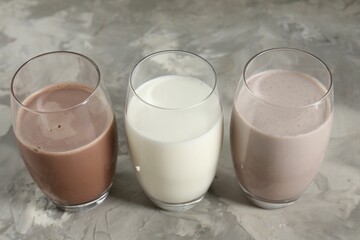 Delicious protein shakes in glasses on gray textured table, closeup