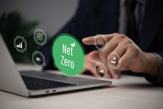 Businessman hand selecting a glowing net zero icon next to environmental symbols.