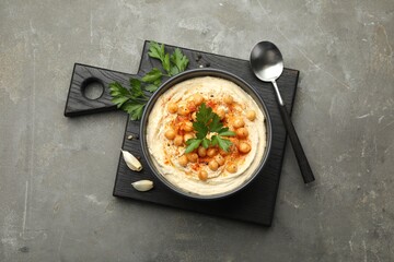 Delicious hummus with parsley, paprika and chickpeas on grey table, top view
