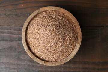 Buckwheat bran in bowl on wooden table, top view